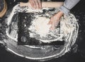 Two female hands knead the dough from white wheat flour on a black table, top view Royalty Free Stock Photo