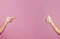 Two female hands pointing and thump up  on pink background Royalty Free Stock Photo