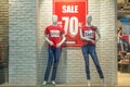 Two female mannequins in red T-shirts and blue jeans in a shop window against a background of a white brick wall Royalty Free Stock Photo
