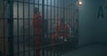 Two female prisoners in orange uniforms talk in prison cell Royalty Free Stock Photo