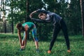 Two female runners doing warming-up bending exercises stretching back and leg muscles before running in park Royalty Free Stock Photo