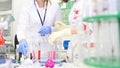 Two female scientist working in laboratory with flasks wearing blue gloves. Two young female scientists working in