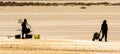 Two female shellfish gatherers walk along the beach shore to prepare to collect clams and mussels.