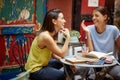 Two female students are chatting while spending a free time at bar`s garden. Leisure, bar, friendship, outdoor Royalty Free Stock Photo