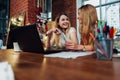 Two female students having a friendly conversation discussing sitting in front of laptop