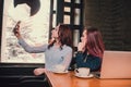 Two female students or lesbians having fun during coffee break at cafe, second half distract from work. Royalty Free Stock Photo