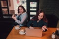 Two female students or lesbians having fun during coffee break at cafe, second half distract from work. Royalty Free Stock Photo