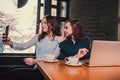 Two female students or lesbians having fun during coffee break at cafe, second half distract from work. Royalty Free Stock Photo