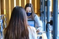 Two female students wearing face masks working on their computers in a restaurant. New normal in restaurants. Royalty Free Stock Photo