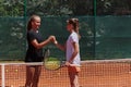 Two female tennis players shaking hands with smiles on a sunny day, exuding sportsmanship and friendship after a