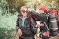 female tourists travel through the forest with trekking backpacks. Friends check each other`s equipment and have fun