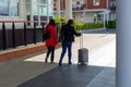 Two female tourists walking together one is pushing a suitcase with four wheels