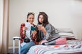 two female travelers look at tickets and cell phones on bed