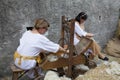 Working with an original medieval loom two female workers making yarn of wool