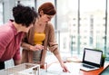 Female young architects with model of a house standing in office, talking.