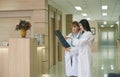 Two females doctor examining and discussing patient's x-ray film in corridor of hospital Royalty Free Stock Photo