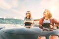 Two females friends traveling by cabriolet, have a stop brake to enjoy a mountain landsxapes