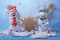 Two festive snowmen on a blue background. Between them is a brown bag with gifts. Snowing. The holiday is coming soon.