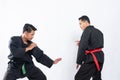 Two fighters in pencak silat Hitam uniform fight in low stance and side stance movements