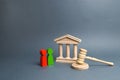 Two figures of people opponents stand near the courthouse and the judge`s gavel. Conflict resolution in court, claimant Royalty Free Stock Photo