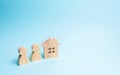 Two figures of people and a wooden house on a blue background. The concept of affordable housing and mortgages for buying a home