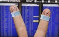 Two finger face with masks keaping a social distance in front of flight timetable on airport Royalty Free Stock Photo