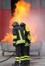 Two firefighters during the exercise with a tank full fire and t