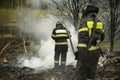 Two firefighters extinguish fire with water. People are holding hose. Rescuers are fighting fire Royalty Free Stock Photo