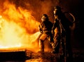 Two firefighters fighting fire with a hose and water Royalty Free Stock Photo