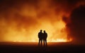 Two firefighters observing a raging wildfire at night Royalty Free Stock Photo