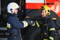 Two firefighters in protective clothing in helmets with fire engine, friendly handshake Royalty Free Stock Photo
