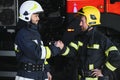 Two firefighters in protective clothing in helmets with fire engine, friendly handshake Royalty Free Stock Photo