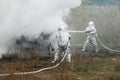 Two firefighters in protective suits works with water hose. Fighting for a fire attack Royalty Free Stock Photo