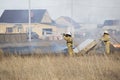 Two firefighters spraying high pressure water. Fire, burning old grass in field. Azov German national district of Omsk region,