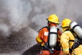 two firefighters water spray by high pressure nozzle to fire surround with smoke and copy space