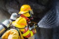 two firefighters water spray by high pressure nozzle to fire surround with smoke and copy space