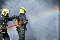 Two fireman or firefighters stand and help each other to spray of water with curtain shape and rainbow reflex occur on water Royalty Free Stock Photo