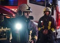 Two firemen wearing a protective uniform standing next to a fire truck. Arrival on call at night time Royalty Free Stock Photo