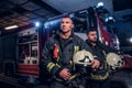 Two firemen wearing protective uniform standing next to a fire truck in a garage of a fire department. Arrival on call Royalty Free Stock Photo