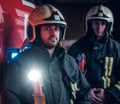 Two firemen wearing protective uniform standing next to a fire truck in a garage of a fire department. Royalty Free Stock Photo