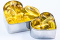 Two fish oil pill containers with pills in heart shape box Royalty Free Stock Photo