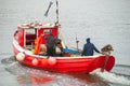 Two fishermen aboard a moving small red fishing boat Royalty Free Stock Photo