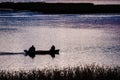 Two fishermen in the boat on a lake in the early morning sunrise, selective focus Royalty Free Stock Photo