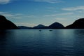 Two fishermen with fishing boats fishing in front of a scenic mountains Royalty Free Stock Photo