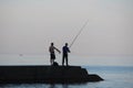 Two fishermen are fishing on a pier in the sea Royalty Free Stock Photo