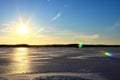 Two fishermen on a frozen lake catch fish in a hole of ice on the background of evening sunset. Winter arrives, bodies of water Royalty Free Stock Photo