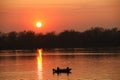 Two fishermen, a man and a woman, swim in a motor boat on the river against the background of an orange sunset. Romantic Royalty Free Stock Photo