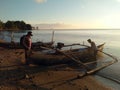 Two fishermen are preparing a traditional fishing canoe on the beach