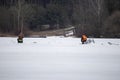 Two fishermen sit on boxes on thin spring ice far from the shore and fishing. Royalty Free Stock Photo