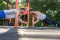 Two young men clapping hands from plank position during partner workout in park